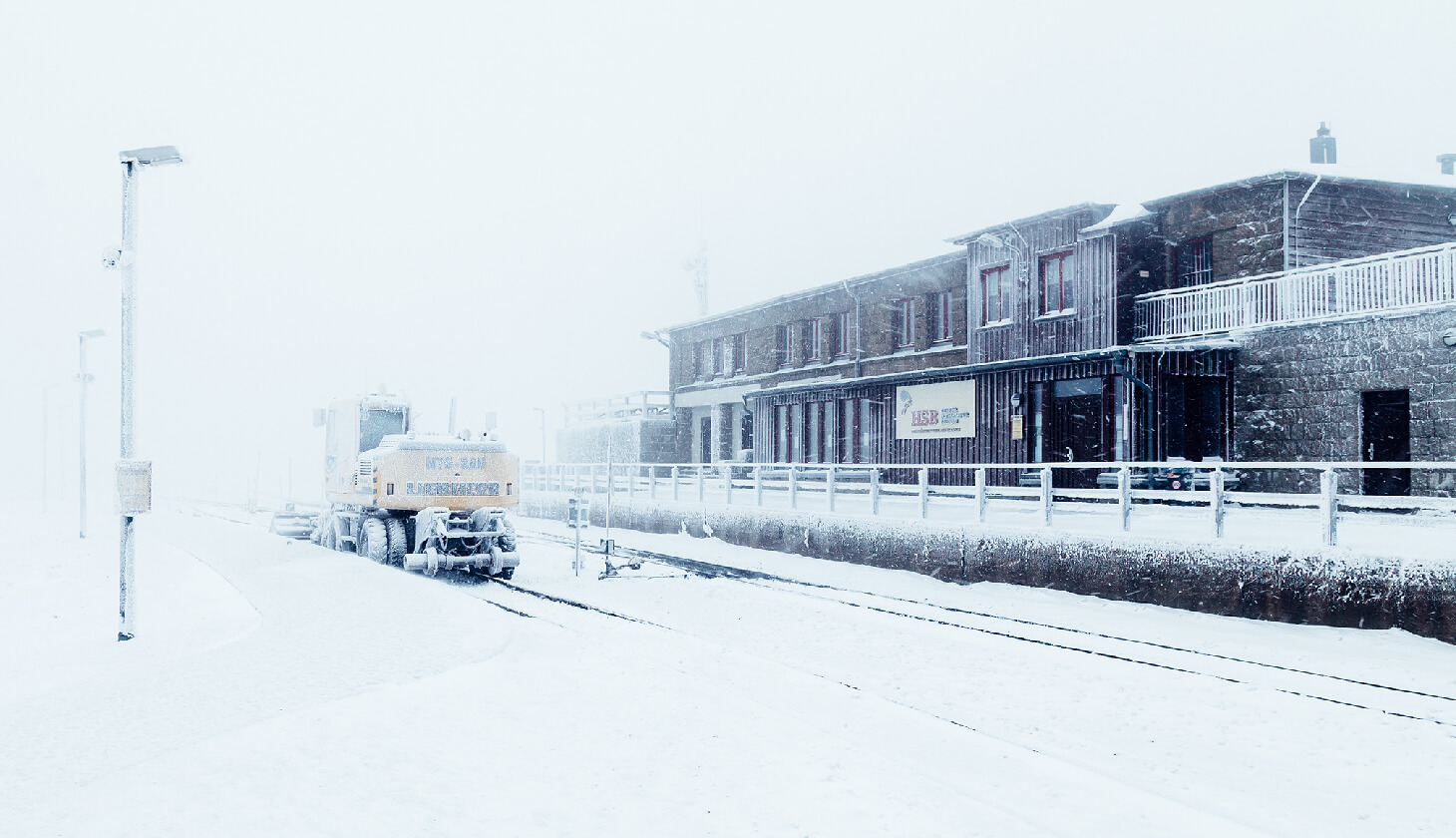 Snow-covered station with train and building.