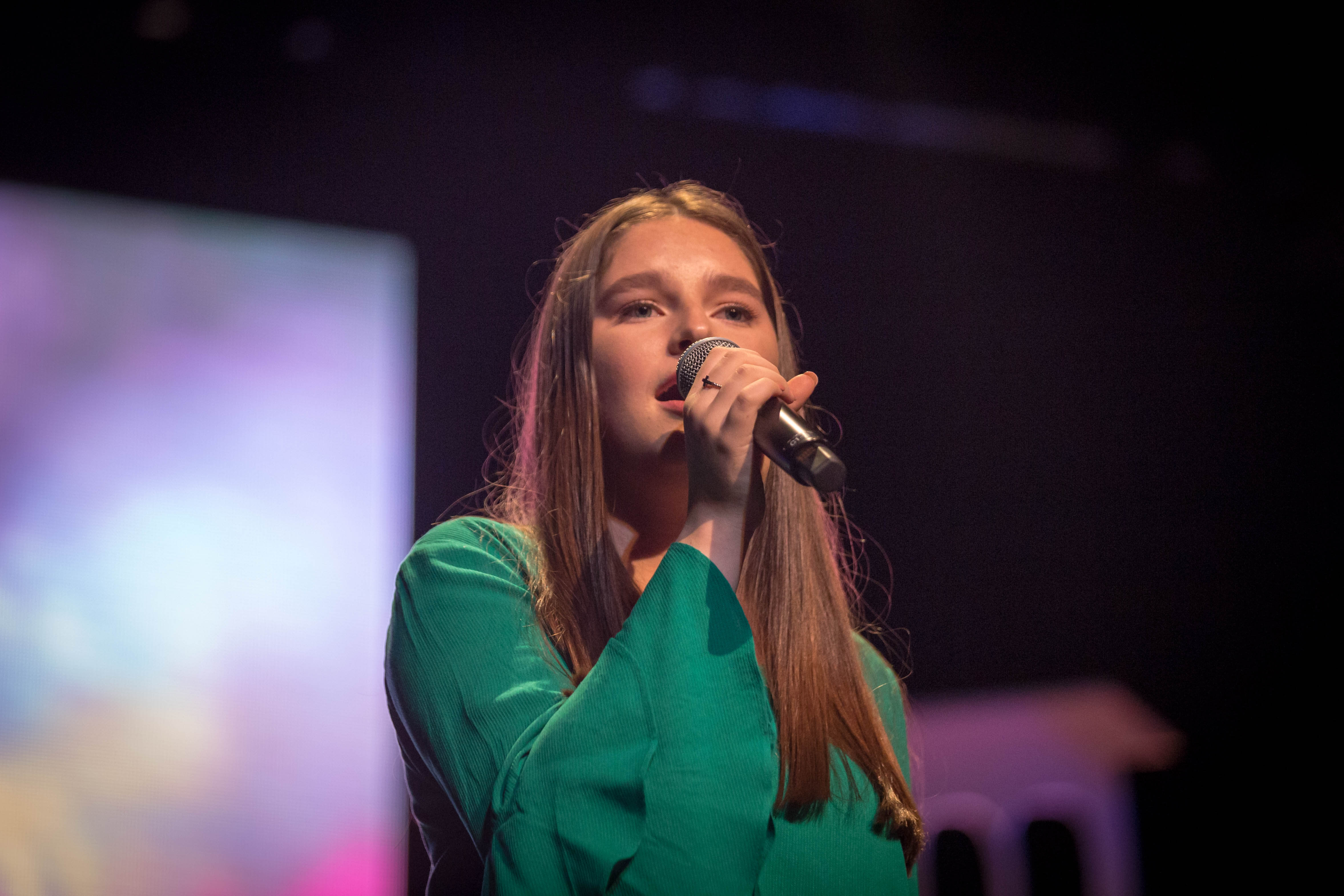 Person singing on stage with microphone.