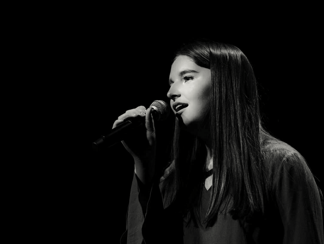 Singer performing with microphone on stage.